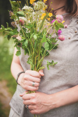 Fototapeta na wymiar Woman hands with meadow flowers bouquet in summer