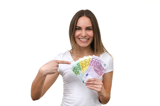 Hübsche blonde Frau zeigt auf Euro-Geldscheine in ihrer Hand und lacht