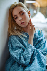 Portrait of young sad woman next to window.