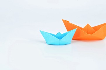 Obraz premium Origami boats orange and blue o white background.