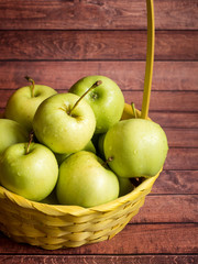 Green ripe apples in a wicker yellow basket