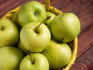 Green ripe apples in a wicker yellow basket