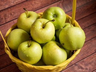 Green ripe apples in a wicker yellow basket