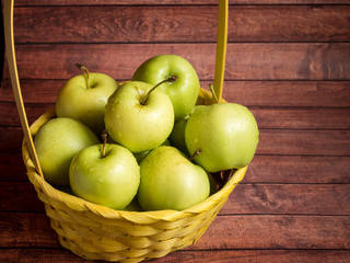 Green ripe apples in a wicker yellow basket