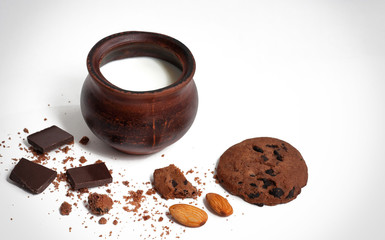 biscuits, chocolate and nuts next to a jug of milk ga white background