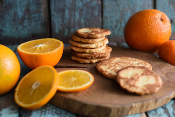 Healthy sweets. Pile of homemade vegetarian cookies and orange slices on wooden slab on shabby blue background
