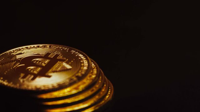 Macro shot of bright golden bitcoins lying in column and rotating