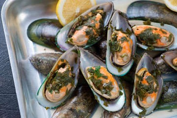 Close-up of green mussels stewed in white wine with parsley, selective focus
