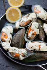 Close-up of baked kiwi mussels with cheese sauce and lemon, selective focus, vertical shot