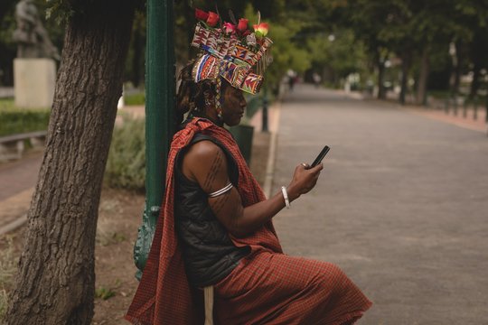 Maasai man in traditional clothing using mobile phone