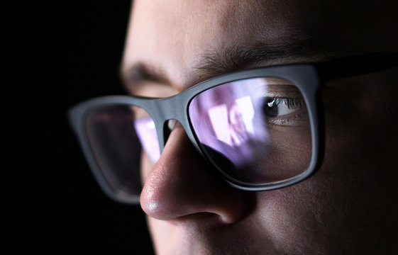 Man Using Online Dating Application With Smartphone Or Watching A Picture Of A Young Woman. Video Phone Call. Long Distance Relationship. Stalker Watching Photos. Reflection Of Screen On Glasses.