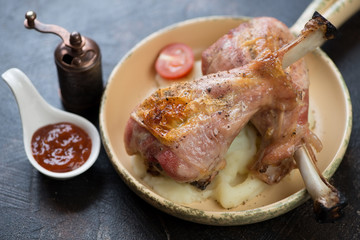 Serving pan with roasted turkey legs on a bed of mashed potato, studio shot