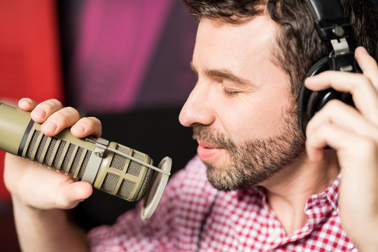 Hispanic young man recording a song in radio studio