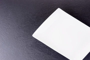 Empty white ceramic bowl on black slate plate with copy space