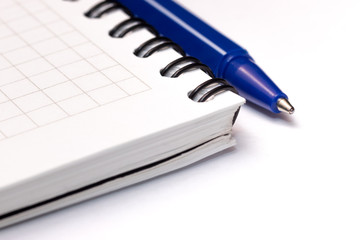 Blue ball pen on blank note book on white background. Close-up macro view