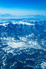 Airplane view on the beautiful alpine mountains top, covered with ice.