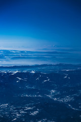Fototapeta premium Airplane view on the beautiful alpine mountains top, covered with ice.