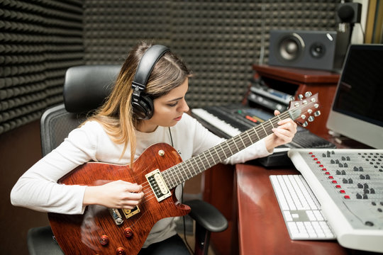 Female guitarist composing music in studio