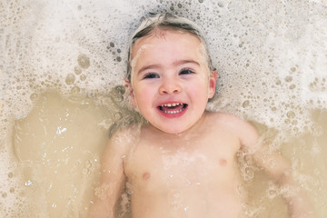 Adorable bath baby girl with soap suds on hair