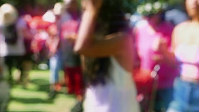 Seamless loop of defocused colorful crowd in slow motion at a festival. Filmed out-of-focus, with a lens flare effect, so the people are unrecognizable.