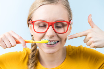 Woman smiling cleaning teeth with braces