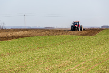 Obraz premium Tractor cultivating field at spring