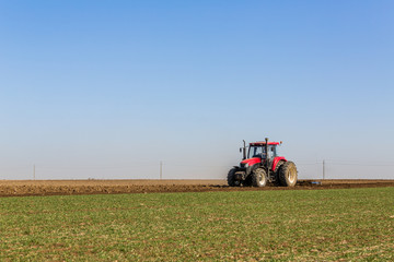 Obraz premium Tractor cultivating field at spring