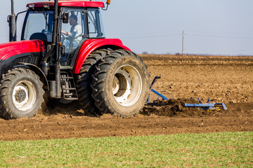 Obraz premium Tractor cultivating field at spring