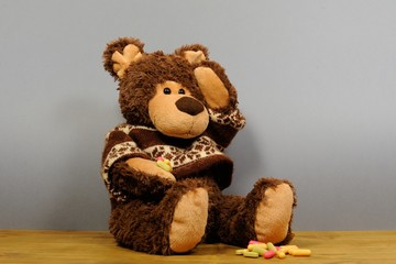 Teddy bear with a headache on gray background. Person having temperature and headache. Bear Toy is ill.