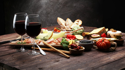 Italian antipasti wine snacks set. Cheese variety, Mediterranean olives, pickles, Prosciutto di Parma with melon, salami.