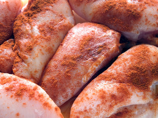 Many raw sliced chicken pieces well sprinkled with red pepper, are ready for baking