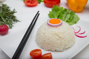 Rice with vegetables on white plate on light background