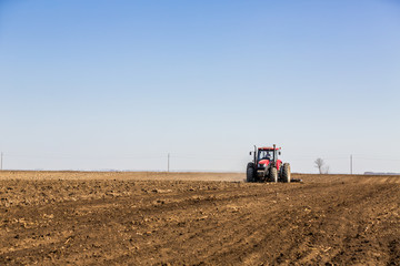 Tractor cultivating field at spring