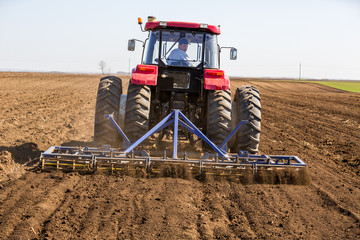 Fototapeta premium Tractor cultivating field at spring