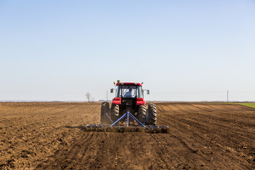 Fototapeta premium Tractor cultivating field at spring