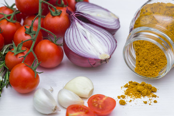 Bunch of tomatoes with garlic, rosemary and curry on white background