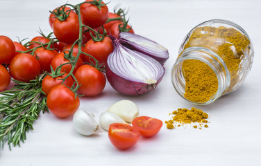 Bunch of tomatoes with garlic, rosemary and curry on white background
