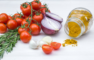 Bunch of tomatoes with garlic, rosemary and curry on white background