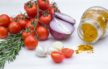 Bunch of tomatoes with garlic, rosemary and curry on white background