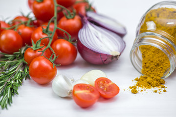 Bunch of tomatoes with garlic, rosemary and curry on white background