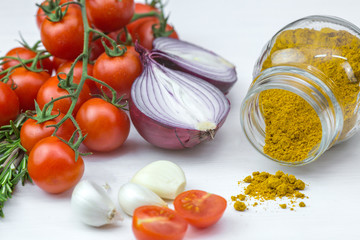 Bunch of tomatoes with garlic, rosemary and curry on white background