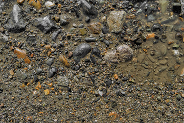 Stone background. Wet ground and stones. Natural background. Stony ground. Puddle. Stony soil. Gravel. Abstract background