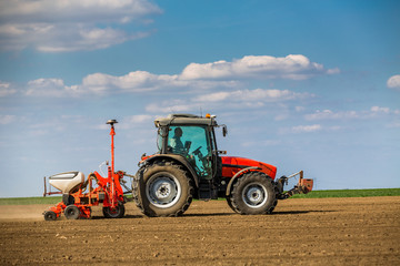 Obraz premium Farmer seeding, sowing crops at field. Sowing is the process of planting seeds in the ground as part of the early spring time agricultural activities.