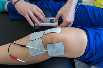 electronic therapy on knee used to treat pain. selective focus