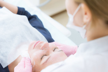 Obraz premium A close-up of the cleaning procedure in the office of cosmetology. Cleaning of the skin with foam. Beautiful girl in beauty salon on facial cleansing procedure. Cosmetologist's job.