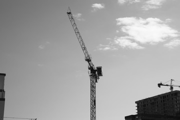 Tower building crane against the blue sky and sun. Construction of new buildings with a crane. Tower crane