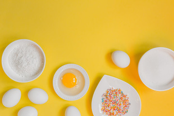  concept of the Easter bakery, various products for home baking, sugar, eggs and flour, coconut munt, top view, empty space for text on a yellow background in the style of pop art mocap layout
