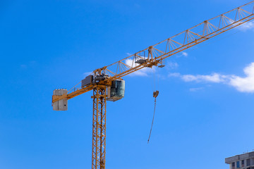 Tower building crane against the blue sky and sun. Construction of new buildings with a crane. Tower crane