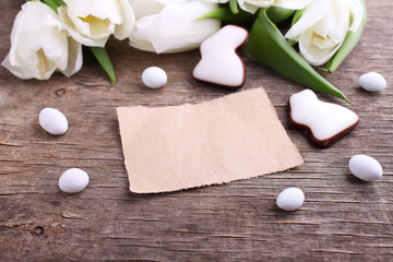 Fototapeta na wymiar Happy Easter greeting card with white tulip and chocolate eggs and bunny, rustic background.
