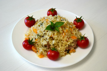pilaf on a white plate with red tomatoes